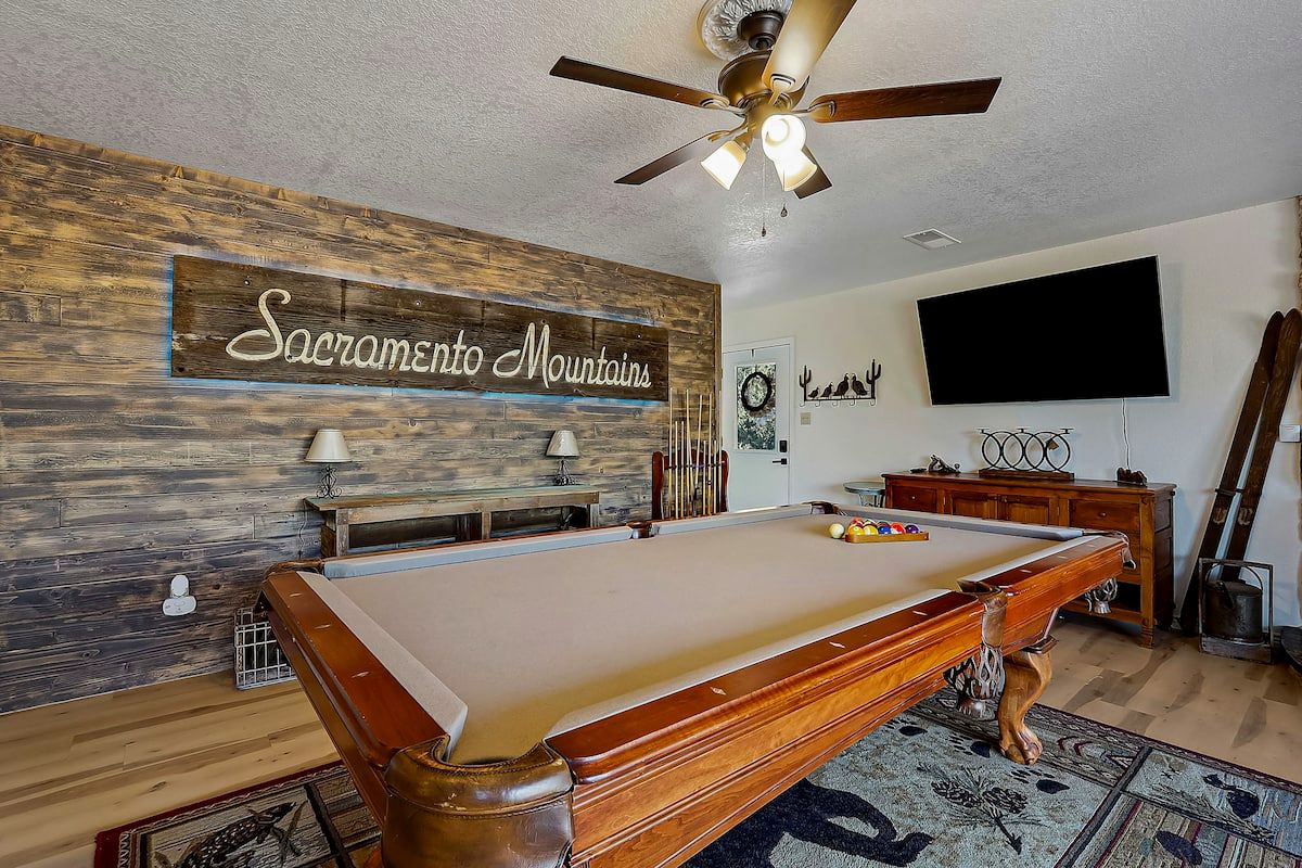 Downstairs den with pool table under a Sacramento Mountains sign