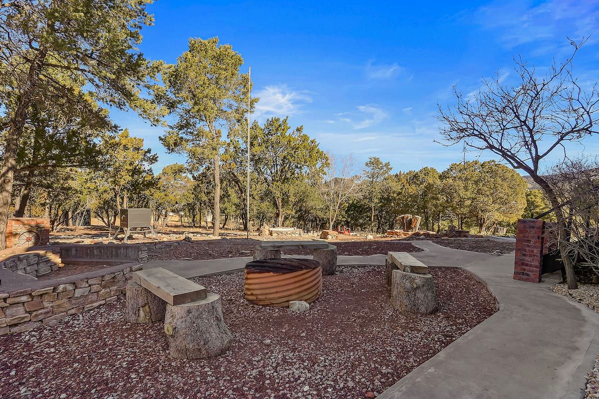 Stone-lined fire pit with log benches among the pines at a High Rolls, NM cabin rental