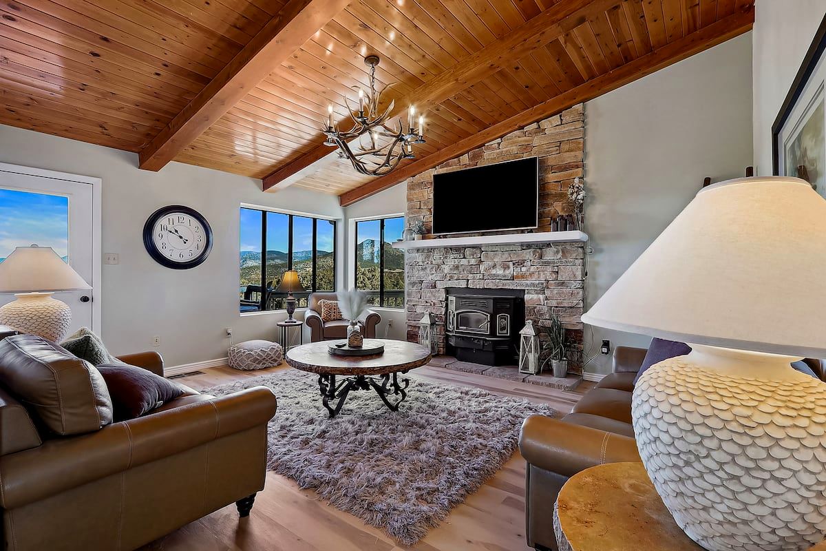 Living room at White Wolf Lodge with wood-beam ceiling, stone fireplace and leather sofas